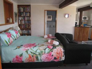 a bedroom with a bed with a flowered blanket and a chair at Seaview holiday Unit - Ohope Beach in Ohope Beach