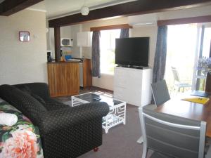 a living room with a couch and a flat screen tv at Seaview holiday Unit - Ohope Beach in Ohope Beach