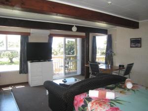 a living room with a couch and a tv and some windows at Seaview holiday Unit - Ohope Beach in Ohope Beach