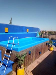 une piscine bleue avec une échelle à côté d'un mur en briques dans l'établissement Riad Zinnha, à Marrakech