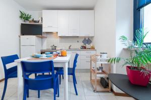 cocina con mesa blanca y sillas azules en Easy flat, en Trento