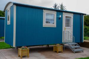 uma casa azul com uma escada e duas mesas em Shepherd Hut Bird Enniskillen, Fermanagh em Enniskillen