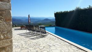 two chairs and an umbrella next to a swimming pool at House Lunja in Vižinada