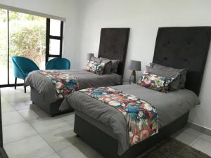 a bedroom with two beds and a chair and a window at The Gamtoos Ferry Hotel in Jeffreys Bay