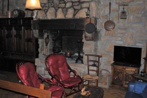 a living room with two red chairs and a fireplace at Natursteinhaus in Portsall in Ploudalmézeau