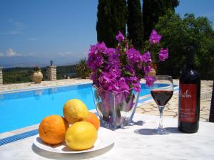a table with a glass of wine and a plate of oranges and flowers at Villa Bacchus Kassiopi Corfu in Kassiopi