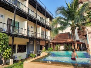 a boy in a swimming pool in front of a building at Prince Hotel Chiang Mai in Chiang Mai