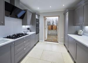 a kitchen with gray cabinets and a stove top oven at Host & Stay - Lowcross Cottage in Guisborough