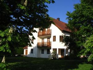 een wit huis met een balkon en bomen bij Pension Eva in Neuhaus am Inn