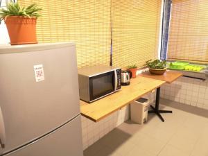 a kitchen with a table with a microwave and a refrigerator at Sunset Homestay - Backpacker Hostel Self Checkin in Kuching