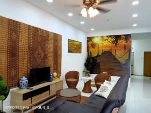 uma sala de estar com um sofá e uma televisão em DAR AS SUFI SUITE em Dungun