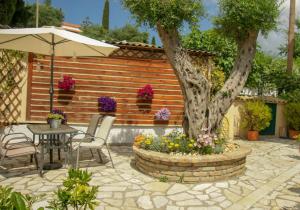 a patio with a table and an umbrella and a tree at Flowers studios in Benitses