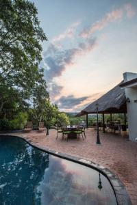 a swimming pool with a table and a patio with at La Roca Guest House in Nelspruit