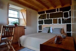 a bedroom with a bed and a stone wall at Caldeira Guesthouse in Fajã da Caldeira de Santo Cristo