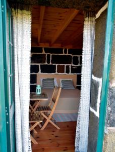 a porch with a bed and a table and chairs at Caldeira Guesthouse in Fajã da Caldeira de Santo Cristo