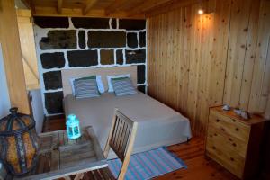 a bedroom with a bed and a stone wall at Caldeira Guesthouse in Fajã da Caldeira de Santo Cristo