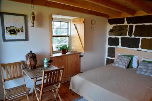 a bedroom with a bed and a table and a window at Caldeira Guesthouse in Fajã da Caldeira de Santo Cristo