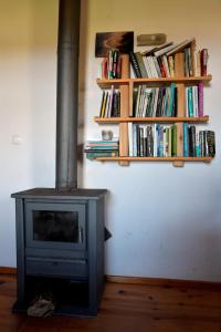 a fireplace in a room with a shelf of books at Caldeira Guesthouse in Fajã da Caldeira de Santo Cristo