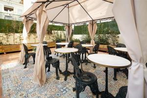 eine Terrasse mit Tischen, Stühlen und einem Sonnenschirm in der Unterkunft Don Cecilio Guesthouse (Centro) in San Sebastián