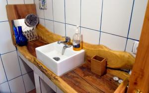 a bathroom with a white sink and a wooden counter at Caldeira Guesthouse in Fajã da Caldeira de Santo Cristo