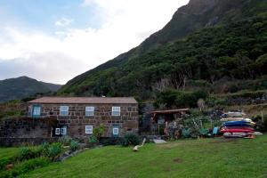 a house in a field with a mountain at Caldeira Guesthouse in Fajã da Caldeira de Santo Cristo