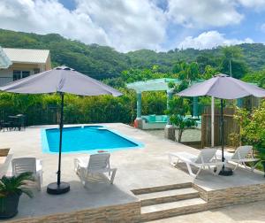 Anse a La Mouche的住宿－格蘭卡茲旅館，一个带两把遮阳伞和椅子的游泳池以及一个游泳池