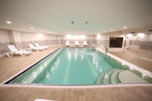 a swimming pool in a hotel with chairs and a tv at EMA ÖZTÜRK THERMAL HOTEL in Afyon