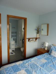 a bedroom with a blue bed and a bathroom at Eildon in Menai Bridge