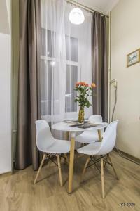 a dining room table with white chairs and a vase with flowers at Kiev Lodging in Kyiv