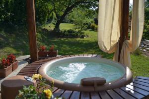 bañera de hidromasaje en una terraza de madera con sombrilla en Baita Naturas con piscina idromassaggio calda, privata e gratuita, en Rossana