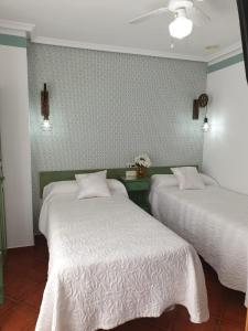 a bedroom with two beds with white sheets and a wall at Don Diego in Ávila