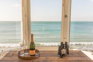 a bottle of wine and glasses on a table in front of a window at Pier View Apartment in Totland