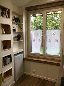 a kitchen with a window and a refrigerator at La ti case - studio de charme au coeur du medoc in Saint-Laurent-de-Médoc