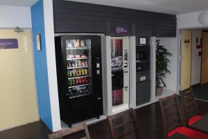 a large soda machine in a room with chairs at Initial by Balladins Béthune in Beuvry