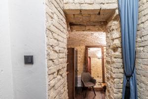 um corredor de tijolos com uma cadeira e uma cortina azul em UNESCO Hidden Arches – Restored 3 Bedroom Apartment in the Historic Pilies St. em Vilnius