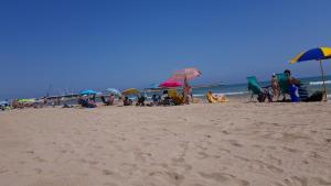 a group of people on a beach with umbrellas at Exclusive Apartment - Playa de Marenys de Rafalcaid in Gandía