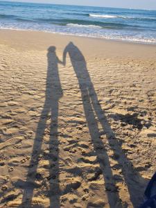 two shadows of people standing on the beach at Exclusive Apartment - Playa de Marenys de Rafalcaid in Gandía