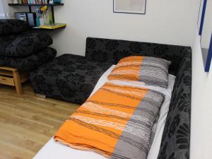 eine Couch mit orangefarbener und grauer Decke drauf in der Unterkunft Ferienwohnung Nimritz in Oppurg