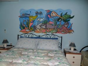 1 dormitorio con 1 cama con una pintura en la pared en B&B Il Mirto en Oristano