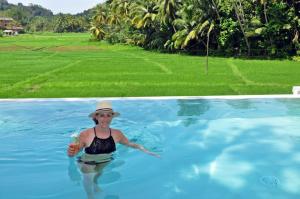 a woman in a swimming pool with a drink at Sugoi House in Unawatuna