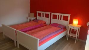 two beds in a bedroom with a red wall at Ca da la nona in Cavigliano