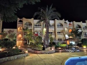 een groot gebouw met 's nachts een palmboom bij One- bedroom apartment S3 in Vip Zone Sunny Lakes in Sharm El Sheikh