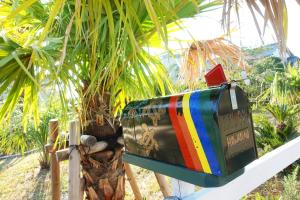 a mailbox sitting on a fence next to a palm tree at HAWAIIAN COTTAGE VILLA SHIRAKO in Shirako