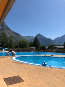 a large swimming pool with mountains in the background at La maison de la montagne in Le Bourg-dʼOisans
