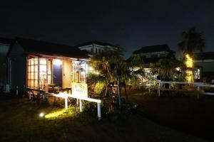 una casa con un cartel delante de ella por la noche en HAWAIIAN COTTAGE VILLA SHIRAKO, en Shirako