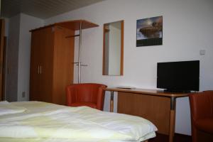 um quarto com uma cama e uma secretária com uma televisão em Pension zur Krone em Eisenach