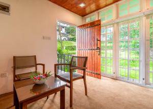 - un salon avec une table, des chaises et des portes coulissantes en verre dans l'établissement Mandaram Eco Resort, à Nuwara Eliya