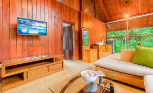 un salon avec un canapé et une télévision au mur dans l'établissement Mandaram Eco Resort, à Nuwara Eliya