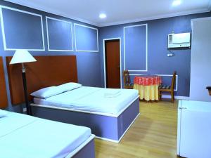 a blue room with two beds and a table at Asiaten Hotel in Tarlac