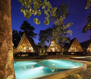 a house with a pool in front of a tree at Kottawatta River Bank Resort in Udawalawe